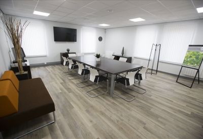 Professional boardroom with a large dark wood table, white chairs, and a presentation screen.