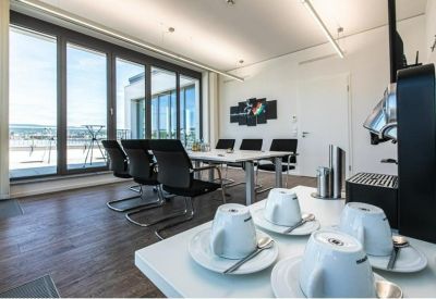 Meeting room with floor-to-ceiling windows and a coffee station with white mugs.