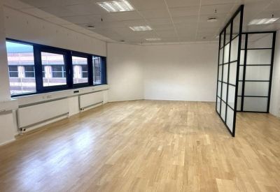 Empty interior office featuring a black-framed glass partition and white walls.