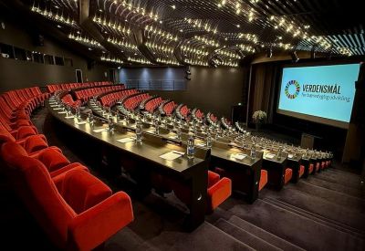 Tiered auditorium with red plush seating and a large projection screen.
