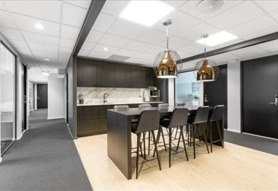 Modern office kitchen and breakout area with high stools and copper light fixtures.
