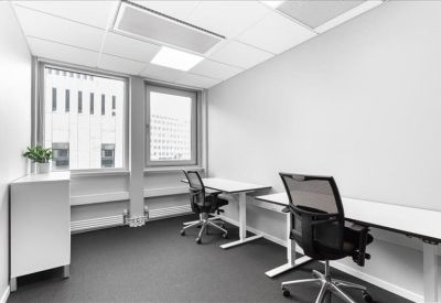 Bright white two-person office with grey carpet and potted plant.