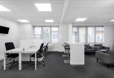 Modern breakout area featuring a white high-top table and grey armchairs.