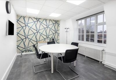 Four-person meeting room with a round table and geometric feature wall.