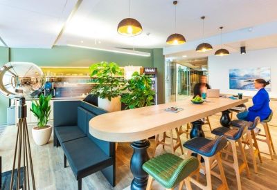 Colorful cafe and breakout area with a long wooden table, plush seating, and hanging pendant lights.
