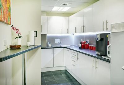 Clean communal kitchen with white cabinetry and a breakfast bar.