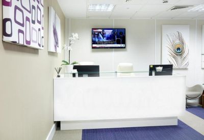 Bright white reception desk featuring a wall-mounted TV and peacock artwork.