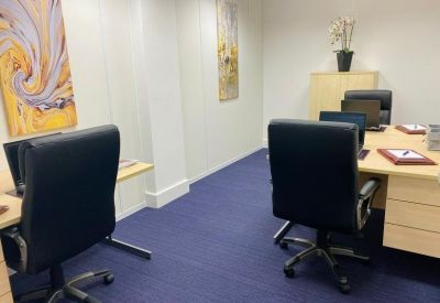 Private office suite with two desks and blue carpet.
