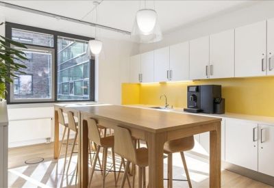 Bright communal kitchen area with a wooden island and yellow splashback.