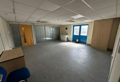 Large empty office room with grey carpet and a blue set of double doors.