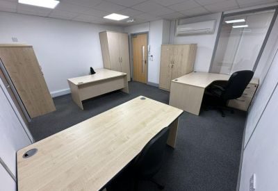 Three-person office suite with light wood desks and matching storage units.