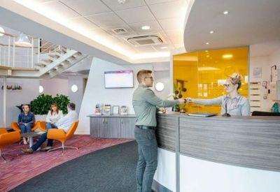 Modern reception desk with a yellow glass feature wall and guest seating.