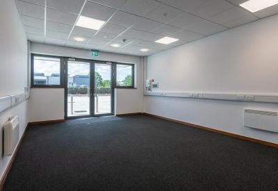 Spacious open office area with glass double doors leading to a parking lot.