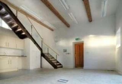 Communal break area featuring white cabinetry and a modern staircase with timber beams above.