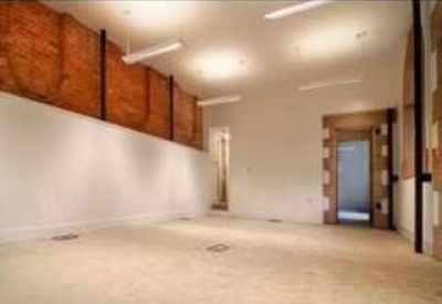 Large open-plan office space featuring a rustic exposed brick wall and white plastered partitions.