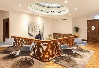Elegant lounge area with a decorative wooden banister and modern armchairs.