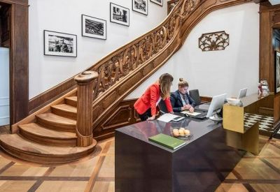 Reception area featuring a grand carved wooden staircase and patterned wood floors.