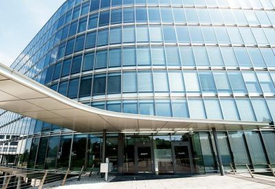 Low-angle shot of the modern glass office entrance under a wide protective canopy.