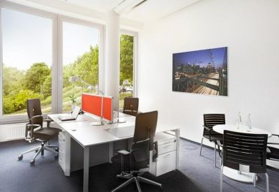 Bright workspace featuring multiple white desks, ergonomic black chairs, and an orange divider.