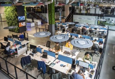 High-angle view of a busy open-plan office with blue desk dividers and indoor vertical gardens.