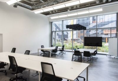Bright meeting room with white tables and large windows overlooking industrial architecture.