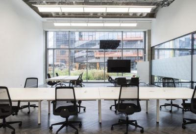 Symmetrical meeting space with long white desks and views of a modern building exterior.
