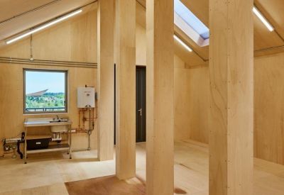 Plywood-lined attic office space with exposed timber columns and skylights.