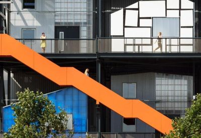 Exterior facade showing a modern industrial building with orange outdoor staircases.