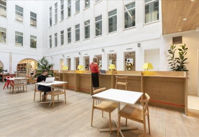 Spacious white atrium with light wood flooring, small café tables, and a high-top counter.