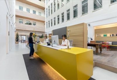 Reception area featuring a vibrant yellow front desk and staff assisting visitors.