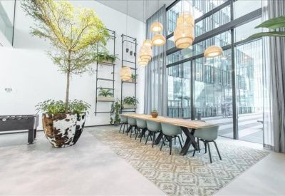 Stylish breakout area featuring a long wooden dining table, hanging wicker lamps, and indoor trees.