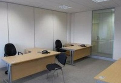 Private office suite with two L-shaped wooden desks and black swivel chairs.
