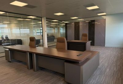 Large office suite featuring multiple executive desks and glass partition walls.