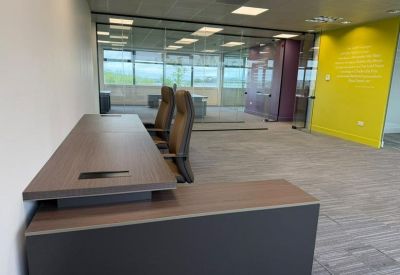 Professional workspace with an L-shaped desk and a bright yellow feature wall.