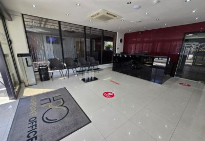 Modern reception area with a sleek black desk, seating area, and red feature wall.