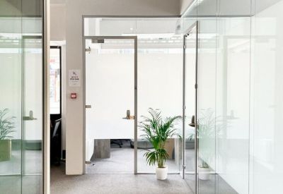 Bright hallway at High Road,, featuring glass partitions and a leafy green potted plant.