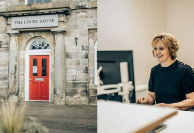 Close-up of a bright red entrance door and a woman working at a computer desk.