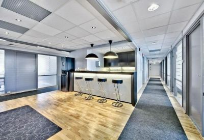 Modern communal kitchen and bar area with sleek cabinetry, black pendant lights, and high bar stools.