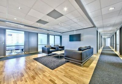Meeting area with black leather sofas, a glass coffee table, and a wall-mounted TV.