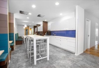 Contemporary breakout kitchen area with a high breakfast bar and vibrant blue and teal wall panels.