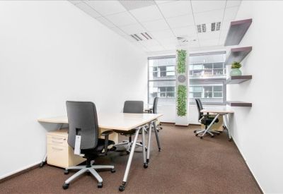 Three-person office suite with light wood desks and a vertical green plant wall.