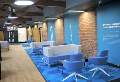 Modern lounge area with blue armchairs, white sofas, and exposed brick accents.