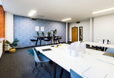 Spacious coworking area with white desks and a blue brick feature wall.