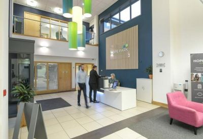 Double-height reception area with colorful pendant lighting and a white front desk.