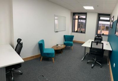 Spacious private office featuring teal accent chairs and a whiteboard.