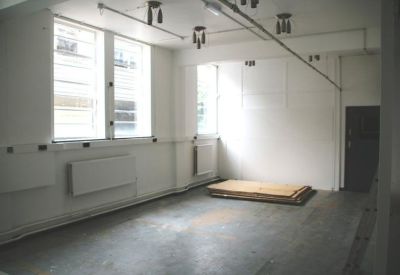Bright, empty office space with white walls and industrial light fixtures.