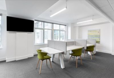 Modern workspace with integrated desks, olive green seating, and a large wall-mounted screen.
