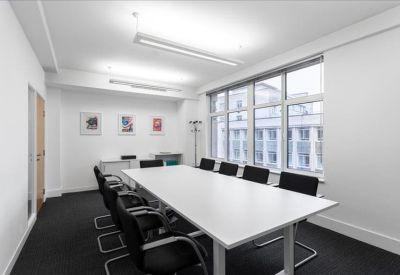 Professional boardroom with a long white table and large windows overlooking the street.