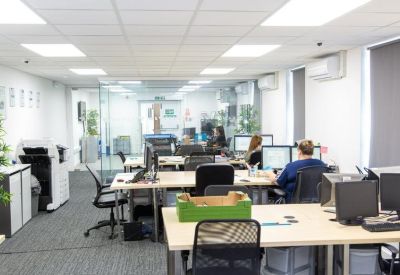 Bright open-plan office with multiple workstations and large windows.