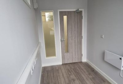 Entryway corridor featuring a wood-textured door and light grey walls.